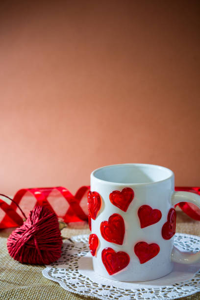 istock composition for st valentine's day with an hart made by a red rope, a white cup with a lot of harts and a red ribbon 870894890