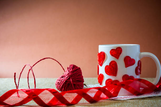 istock composition for st valentine's day with an hart made by a red rope, a white cup with a lot of harts and a red ribbon 870895028