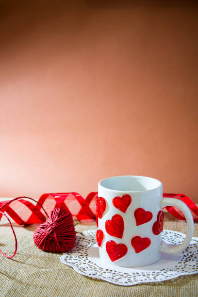istock composition for st valentine's day with an hart made by a red rope, a white cup with a lot of harts and a red ribbon 870895062