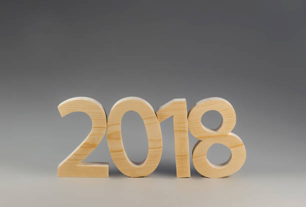 istock Wooden figures forming 2018, carved from light wood on a gray ba 870897802