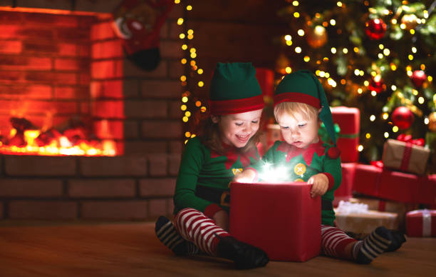 natal. elfos com um presente mágico perto de árvore de natal e lareira - clock baby christmas small - fotografias e filmes do acervo