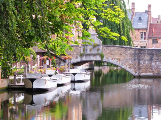 istock Three Boats in Bruges Waterway with Brick Bridge 870898442