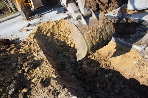 istock Earth mover digging trench across asphalt street 870898610