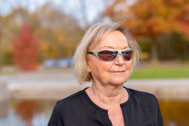 Senior woman wearing trendy modern sunglasses with large lenses as she spends a relaxing day outdoors admiring the colorful autumn colors