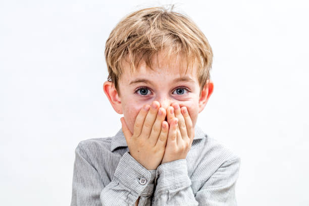 istock joyful boy holding back from bursting out laughing for shyness 870902838