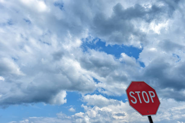 istock Red graphic stop sign contrasts nicely against a bright blue sky and clouds 870905344
