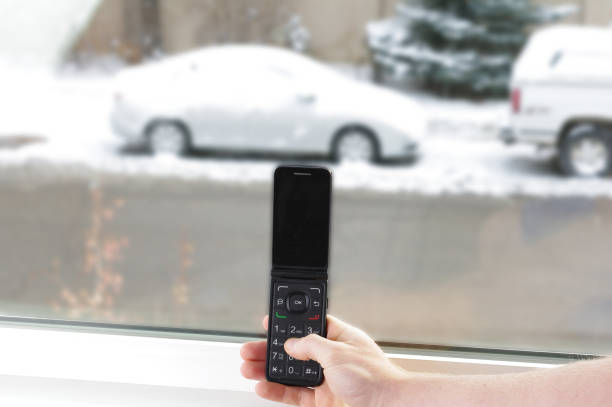 istock Old cell phone in hand with car in snow 870906286