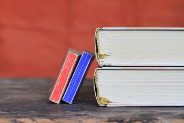 An opened book on the top of the stack of blue books, symbol of knowledge, yellow, light, copy space, studio shot.