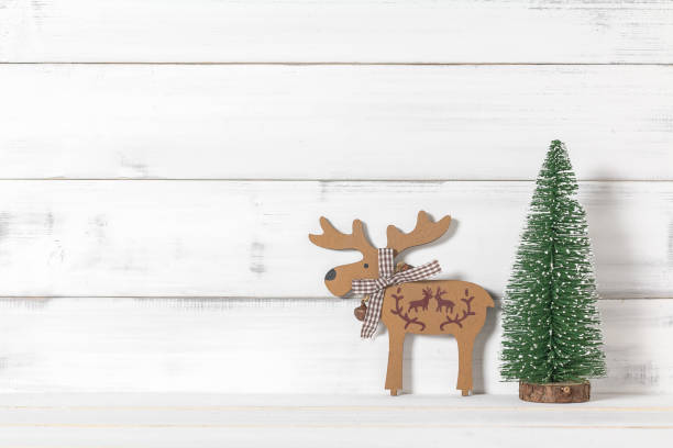 istock Wooden reindeers with christmas tree on white wood over white rustic background with copy space for text 870909612