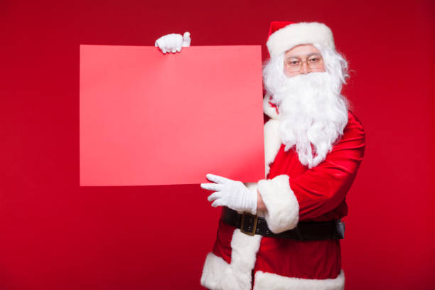 istock Santa Claus pointing in blank advertisement banner isolated on red background with copy space red leaf 870909674