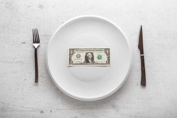 parte superior de la vista un dólar billete en el plato blanco con tenedor y cuchillo. - dinner currency table business fotografías e imágenes de stock