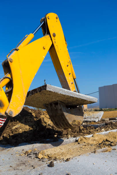 istock Earth mover digging, pulling up large asphalt block from the street 870938218