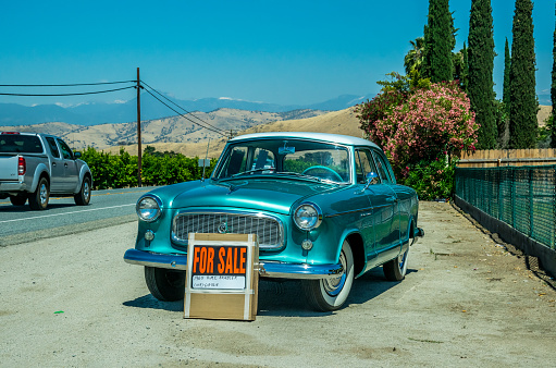 Three Rivers, California, USA - June 15, 2017: Roadside and old retro car put up for sale. Picturesque highway in the countryside in California, USA and selling an old car. Road to the Sequoia National Park