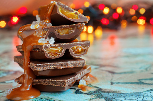 Macro chocolate pieces with caramel and sea salt against holiday background