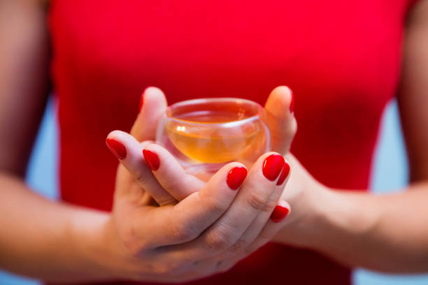 Cup of tea in woman's hands with red manicure