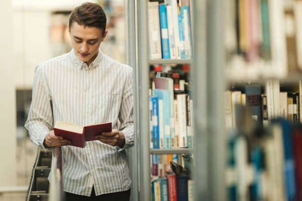 istock Man stsnd on the library and read book with blur background sun light 870971580