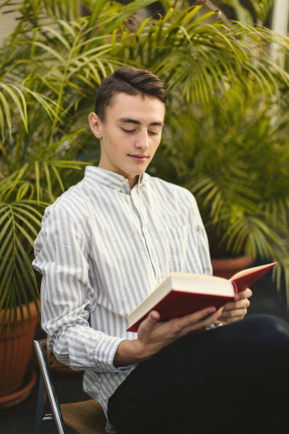 istock Man sit on the library and read book with blur background 870971694