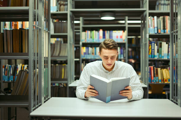 istock Man sit on the library and read book with blur background 870971710