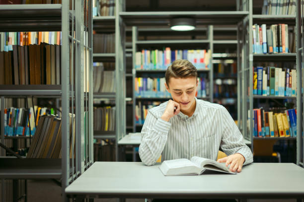 istock Man sit on the library and read book with blur background 870971736