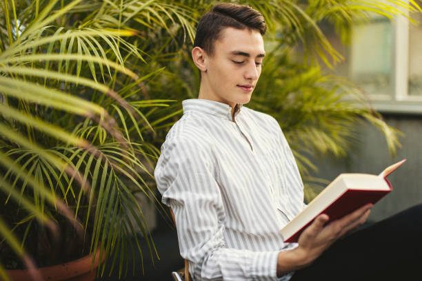 istock Man sit on the library and read book with blur background 870971740
