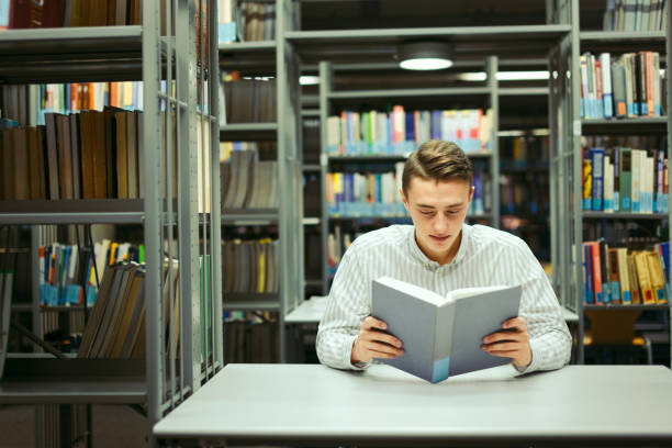 istock Man sit on the library and read book with blur background 870971754