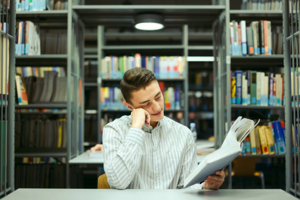 istock Man sit on the library and read book with blur background 870971784