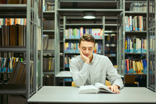 istock Man sit on the library and read book with blur background 870971906