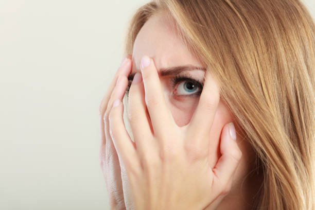 istock Afraid frightened woman peeking through her fingers 870981370