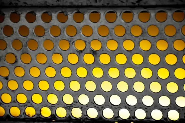 Closeup of holes in a single step of a stairway with a golden/yellow background