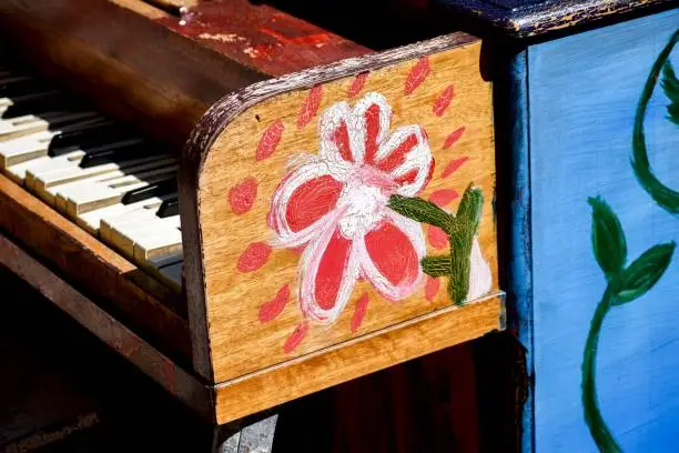 Side view of a piano outside with a flower painted on i