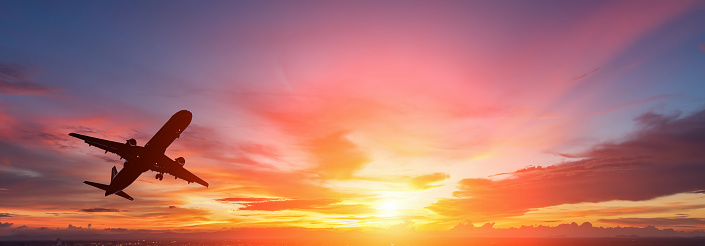 The silhouette of a passenger plane flying in sunset.