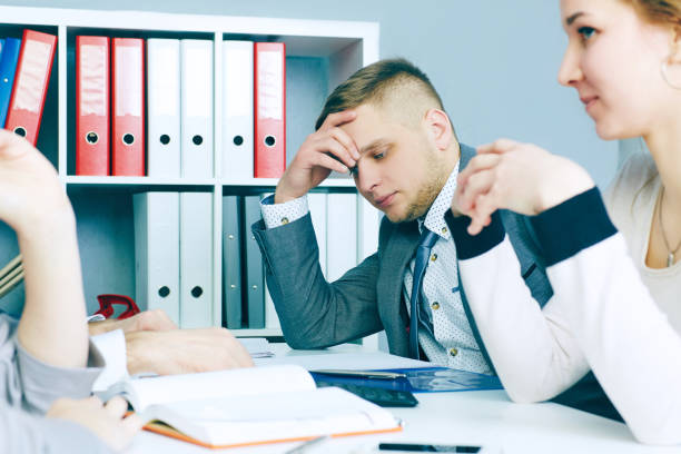 istock Pensive young handsome man looking on his colleague while sitting at the office table on business meeting. 871012814