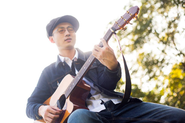 istock low angle view of young man playing acoustic guitar 871028194