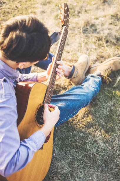 istock young man playing acoustic guitar on lawn 871028258