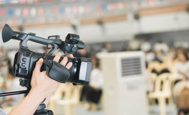 istock Hand control video camera operator camcorder working with his equipment outdoor with blurred background 871037254