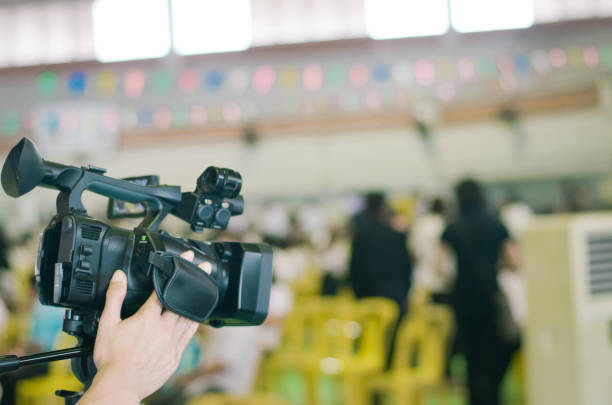 istock Hand control video camera operator camcorder working with his equipment outdoor with blurred background 871037272