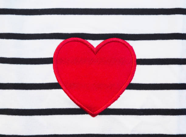 Red heart shape wool on white fabric with black stripes texture.