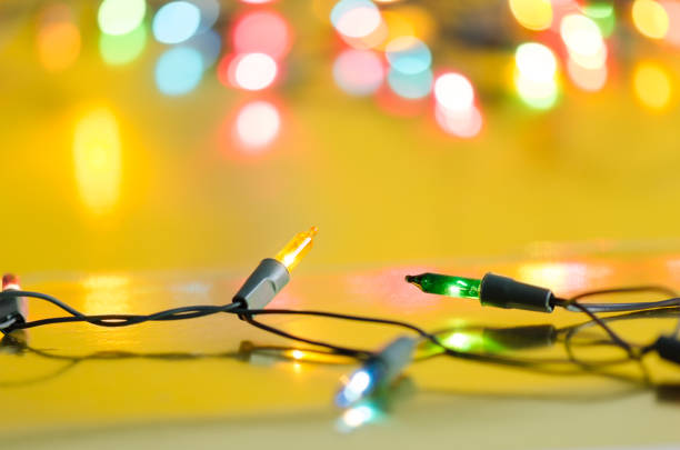 istock Xmas light bulbs on string in multi colours; blue, yellow, green, pink & red on gold yellow background with copy space & bokeh (blur light) for Christmas, new year celebration (tree ornament concept) 871049918