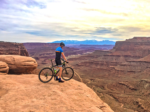 a man mountain bikes against the grand and majestic desert badlands southwest landscape.