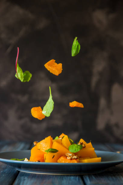 istock Salad with pumpkin, walnuts and green leaves, levitation ingredients 871056888