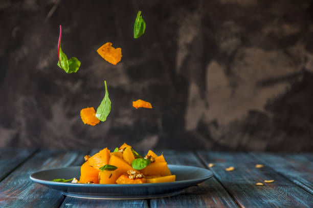 istock Salad with pumpkin, walnuts and green leaves, levitation ingredients 871056906