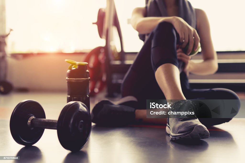 Frau Übung Workout im Fitness-Studio Fitness brechen entspannen hält Apfelfrucht nach dem Training Sport mit Hantel und Protein shake Flasche gesunden Lebensstil Bodybuilding. - Lizenzfrei Fitnesstraining Stock-Foto