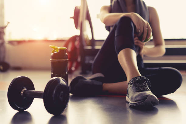 女性エクササイズのトレーニングはジム フィットネス速報にリラックス ダンベルとタンパク質トレーニング スポーツ後リンゴ果実を振るボトル ヘルシー ボディービルを保持しています。 - 練習 ストックフォトと画像