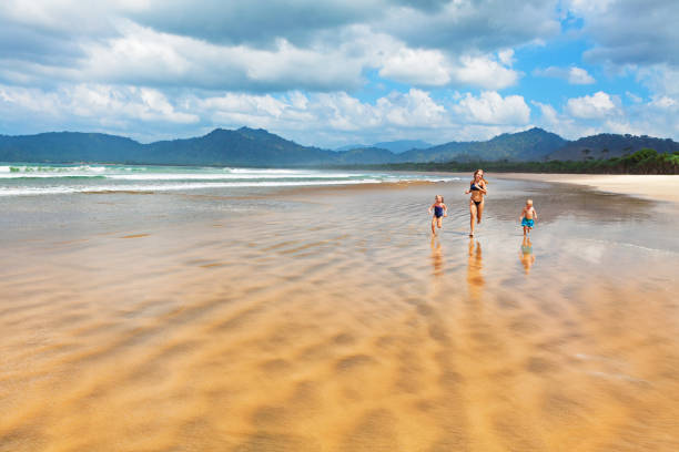 Happy family run by wide sand beach