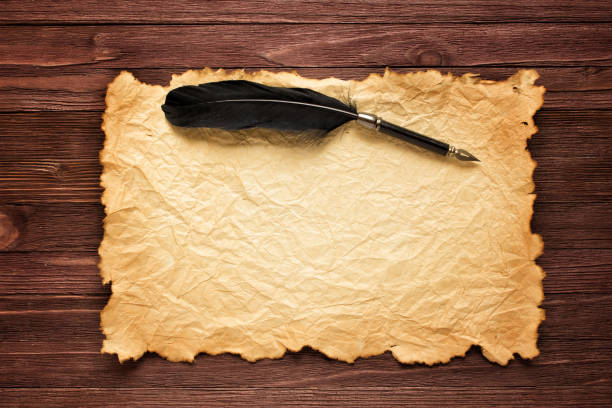 istock Black feather and old paper on the background of a brown table 871071732