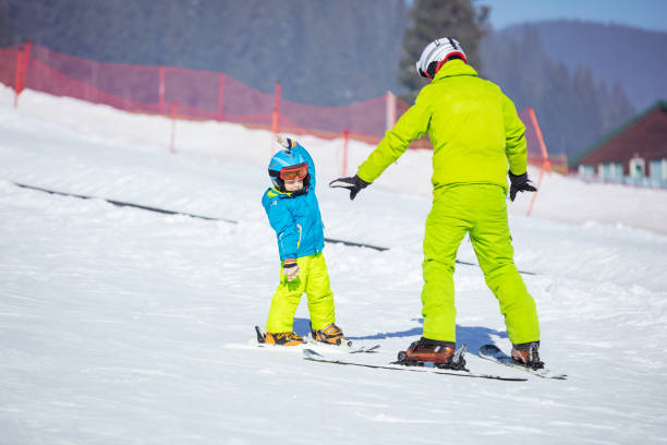 istock Lesson at skiing school: instructor teaching little skier how to make turns 871072608