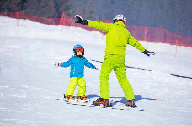 Instructor teaching little boy to ski stock photo