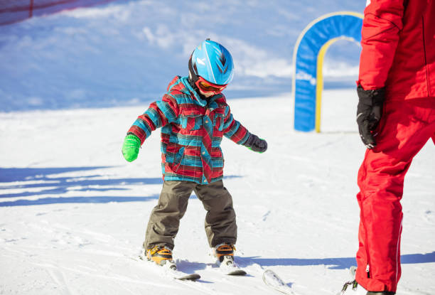 Young skier and ski instructor on slope in beginners' area stock photo
