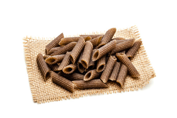 istock Wholegrain raw pasta heap on a burlap tissue isolated on white background 871078070
