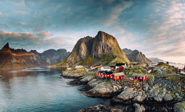 Norwegian fishing village at the Lofoten Islands in Norway. Dramatic sunset clouds moving over steep mountain peaks stock photo